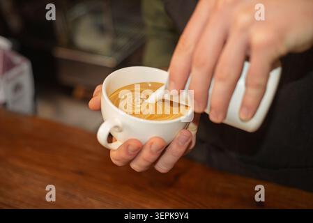 A close up of a barista pouring milk to create latte art Stock Photo