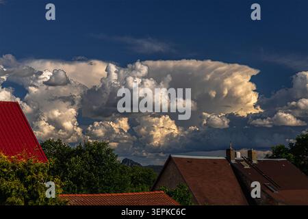 Dramatic cumulonimbus storm clouds forming over rural village houses under a deep blue sky Stock Photo