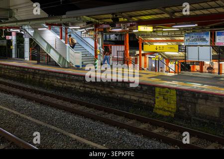 Kyoto, Japan April 19, 2026 fushimi inari night view of train station platform with people walking stairs and illuminated exit signage Stock Photo
