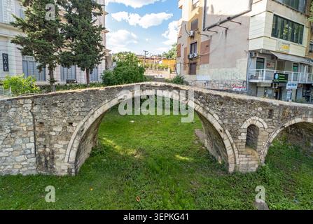 Tanners' Bridge - historic Ottoman-era stone footbridge - surrounded by green grass and city buildings, Tirana, Albania Stock Photo