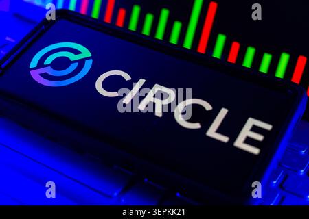 Circle Logo on Smartphone Screen With Stock Market Performance Chart on Computer Stock Photo