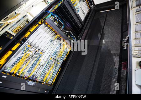 Close-up of high-density network switch chassis with fiber optic patch cords and cable labels in server room. Stock Photo