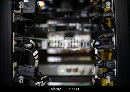 This image shows a professional data center with multiple server racks filled with electronic hardware, networking equipment, and connecting cables, e Stock Photo