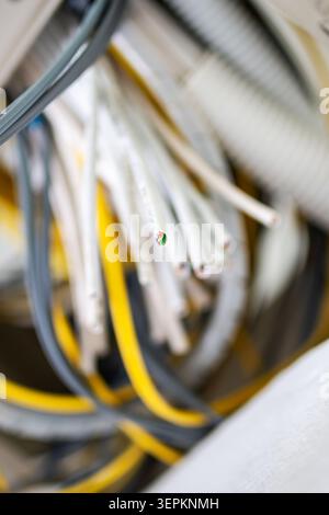 This image depicts a cluster of network cables and connectors in a data center environment, illustrating the complex wiring and infrastructure essenti Stock Photo