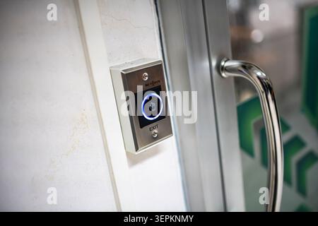 This image features a modern, touchless exit button mounted on a wall, used for accessing or exiting secure indoor spaces with safety and security fea Stock Photo