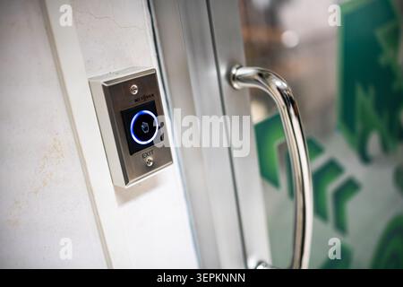 This image features a modern electronic door lock system with a sleek card reader installed on a wall beside a glass door, providing secure access con Stock Photo