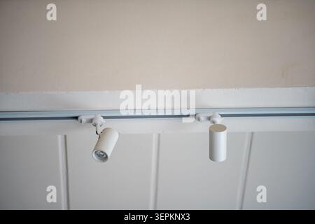 A modern ceiling-mounted track lighting fixture with adjustable spotlights installed on a sleek white ceiling, providing versatile illumination for co Stock Photo