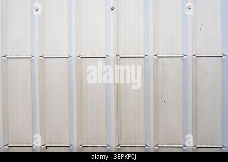 A close-up image of a plain metal wall made of vertical panels, showing a flat surface with minimal texture and neutral color, suitable for industrial Stock Photo