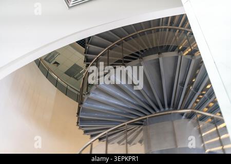 A modern interior scene featuring a sleek, spiral staircase made of metal with curved steps and a stylish railing, showcasing contemporary architectur Stock Photo