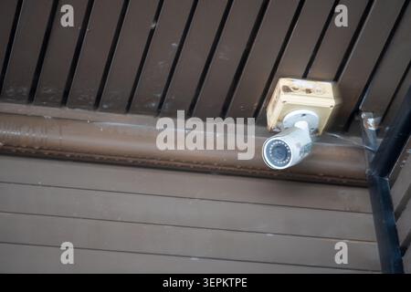 The image shows an electrical outlet and a security camera mounted on a wall with metal paneling, highlighting essential components of security and el Stock Photo
