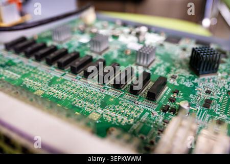 Close-up of a green printed circuit board featuring various electronic components like microchips, resistors, capacitors, and connectors, showcasing a Stock Photo