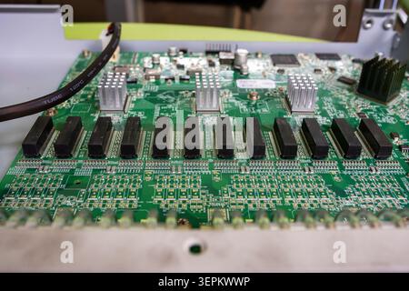 An intricate green printed circuit board featuring black chips, electronic components, and connectors used in electronic devices and hardware systems. Stock Photo