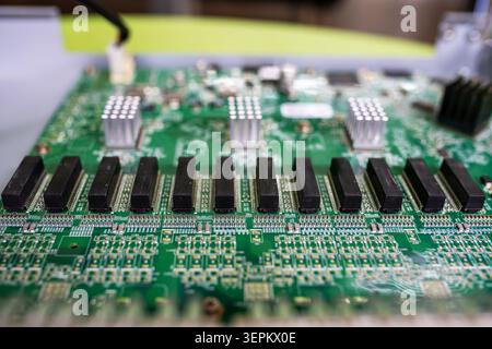 A detailed close-up image showcasing a green printed circuit board with multiple black chips, capacitors, and electronic components, illustrating mode Stock Photo