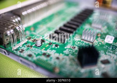 Close-up of a green printed circuit board showing various electronic components, connectors, microchips, and circuitry, illustrating hardware for elec Stock Photo