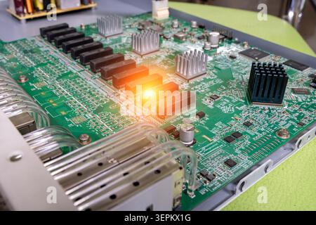 Close-up of a computer server motherboard showing circuit pathways, cooling fins, heat sinks, electronic chips, and various components on a green prin Stock Photo
