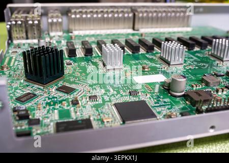 Close-up of a printed circuit board with various electronic components including heatsinks, microchips, resistors, capacitors, and transistors capturi Stock Photo