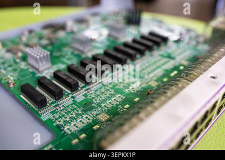A detailed close-up view of a green printed circuit board featuring multiple electronic components, connectors, and integrated circuits used in digita Stock Photo