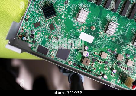 This detailed close-up image showcases a green printed circuit board filled with microchips, capacitors, resistors, and other electronic components us Stock Photo
