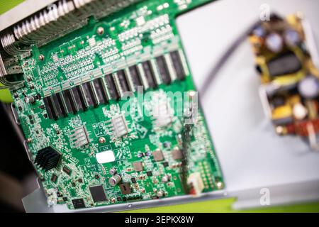 Detailed close-up image of a green printed circuit board featuring various microchips, resistors, capacitors, and electronic connections used in techn Stock Photo