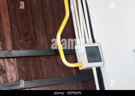 This image shows an electric meter and wiring mounted on a wooden wall, illustrating electrical components used for energy measurement and home power Stock Photo