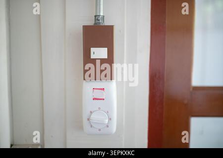 This image shows a building interior featuring an emergency exit light and a fire alarm control system mounted on the wall, designed for safety and al Stock Photo