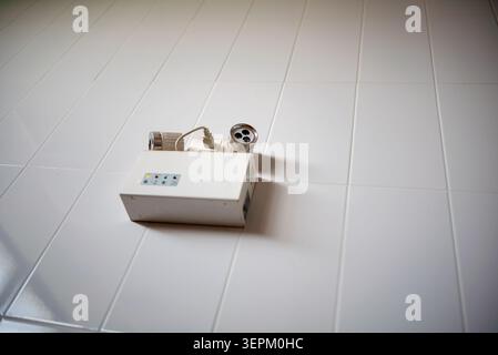This image shows a power strip with multiple outlets and an extension cord lying on a white tiled floor, illustrating electrical connection and power Stock Photo
