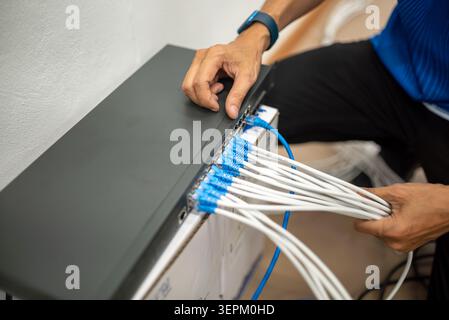 A technician working on a network switch connecting multiple Ethernet cables, highlighting technology setup, data transfer, and network infrastructure Stock Photo