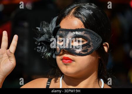 Close-up portrait of a dancer wearing an elegant black lace masquerade mask with a floral ornament and bright red lipstick during a cultural festival Stock Photo