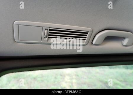 Close-up view of a car interior ceiling featuring a gray air vent and grab handle, highlighting automotive design, passenger comfort Stock Photo