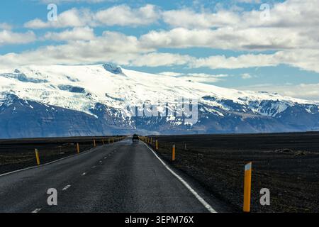 Route 1 road through black sand plains toward snow capped mountains and glaciers in Iceland Stock Photo