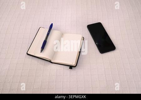 Open empty notebook, pen and mobile phone on fabric Stock Photo