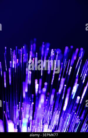 Bright purple fiber optic cables glow against dark blue background creating magic tech texture Stock Photo
