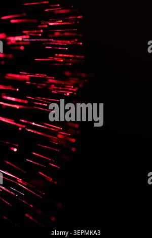 Abstract close up bright red glowing fiber optic cables lines spreading against black background Stock Photo