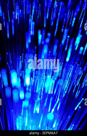 Stunning blue neon light trails and bokeh created by glowing fiber optic cables in dark room Stock Photo
