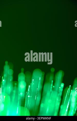Green fiber optic lights illuminating from bottom against dark backdrop Stock Photo