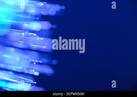 Glowing blue fiber optic tips creating bokeh barrier with large copy space on deep blue background Stock Photo