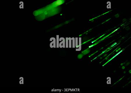 Abstract composition bright green neon fiber optic lines moving diagonally across dark space Stock Photo