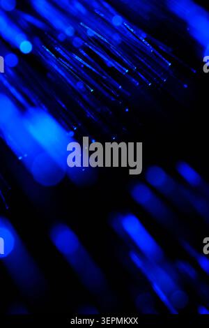 Dynamic blue fiber optic cables with sharp details and blurred light elements in dark Stock Photo