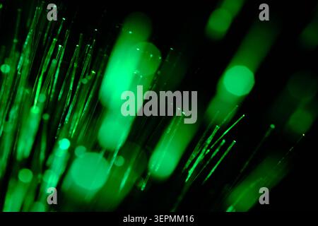 Intense green light leaks and blurred bokeh effects from optical fibers on black backdrop Stock Photo