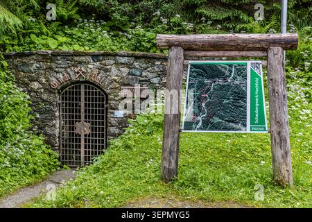 The entrance to the Hieronymus Erbstollen at the Hochfeld exhibition mine in the Untersulzbachtal valley, with an information board featuring a map of the route in front of it. The adit, which is around 400 metres long, was once used for copper mining and today provides access to rock formations up to 450 million years old. Rosental, Neukirchen am Großvenediger, Bezirk Zell am See, Salzburg, 5741, Austria Stock Photo