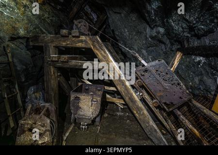 A historic mine wagon made of wood and iron stands beneath a cable-haulage system at the Hochfeld exhibition mine. The haulage system dates from the era of copper mining in the Untersulzbachtal valley, which continued until 1953. Rosental, Neukirchen am Großvenediger, Bezirk Zell am See, Salzburg, 5741, Austria Stock Photo