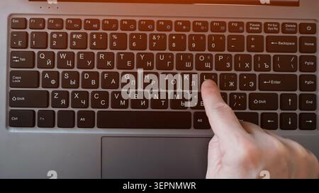 Hand pressing a laptop key in a close up overhead view, highlighting typing, digital communication and remote work productivity in a modern home or Stock Photo
