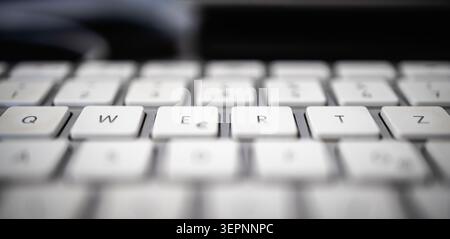 A macro, shallow depth-of-field photograph focusing on the unique multilingual Swiss QWERTZ layout of a white computer keyboard. Stock Photo