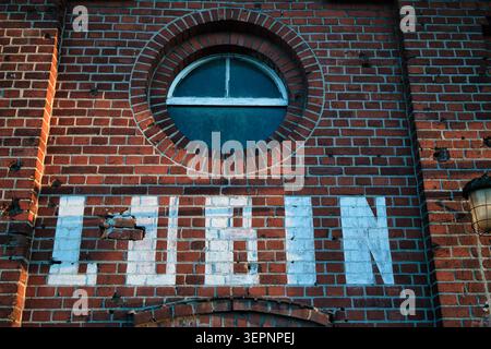 Painted brick Lubin sign with round window on the facade of the rustic railway station building - City of Lubin. Stock Photo