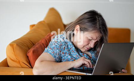 Tired Woman Relaxing. Exhausted Lady Relaxes Quietly At Home. Woman Feeling Drained Rests Comfortably In Her Living Room. Woman Showing Signs Of Stock Photo