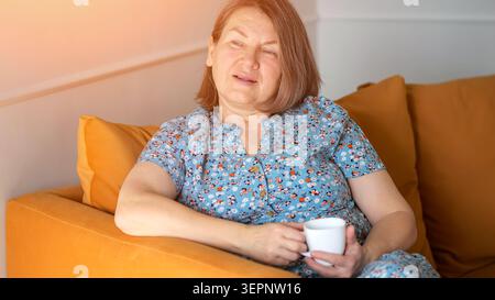 Serene Lady Enjoying Cozy Afternoon. Relaxed Woman Sitting Calmly With Warm Sunlight. Casual Scene Of Woman Resting Comfortably On Orange Couch With Stock Photo