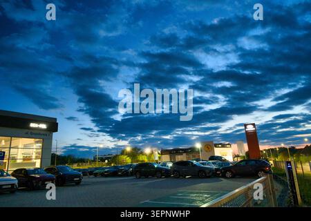 Car Dealership Parking Lot at Dusk With Rows of Cars Under Dramatic Cloudy Sky Stock Photo
