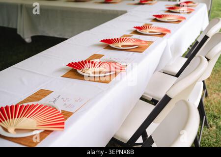 Set tables with red hand fans at a formal event Stock Photo