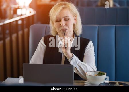 Thoughtful Senior Entrepreneur. Elderly Lady Contemplating Ideas During Meal Break. Older Female Professional Engages In Silent Brainstorming During Stock Photo