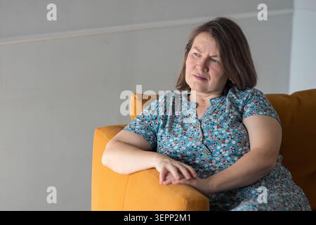 Thoughtful Lady Relaxing With Contemplative Mood. Serene Woman Leaning On Sofa Exhibiting Introspective Demeanor. Quiet Female Immersed In Thought Stock Photo